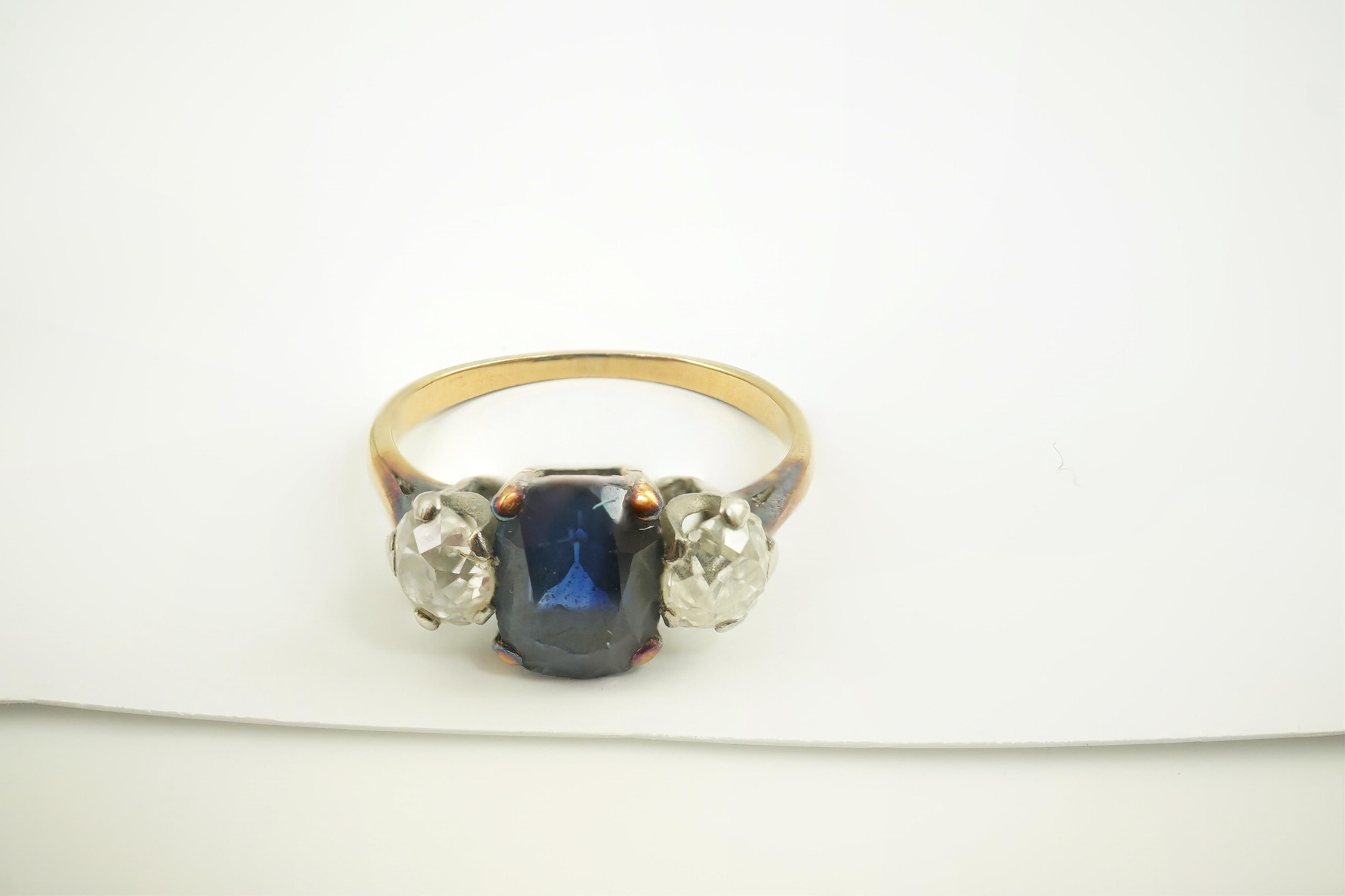 A gold, single stone oval sapphire and two stone round cut diamond set ring